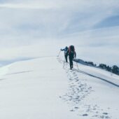 two person climbing on mountain covered snow