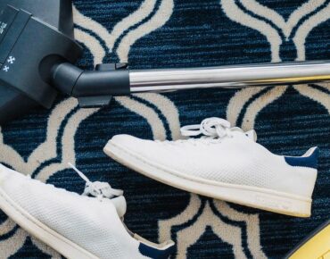 pair of white sneakers beside vacuum cleaner