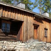 a wooden building with a stone wall and a bench in front of it